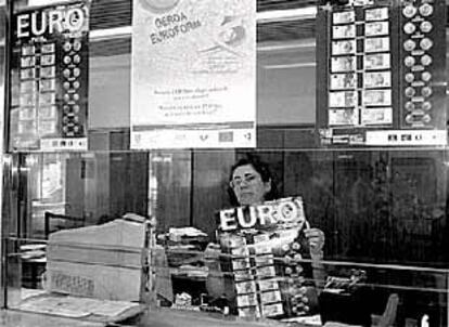 Una empleada colocando carteles sobre los billetes y monedas de euro en una sucursal bilbaína.