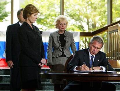 Bush firma en un libro de condolencias por las víctimas del colegio de Beslán, ante la mirada de su mujer, Laura &mdash;de negro&mdash;, del embajador ruso en Estados Unidos, Yuri Ushakov, y de la esposa de éste, Svetlana Ushakova.