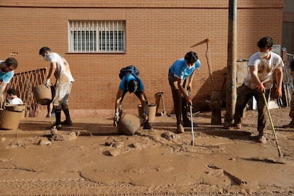 Varios jóvenes trabajan para despejar una calle de Paiporta, este martes.