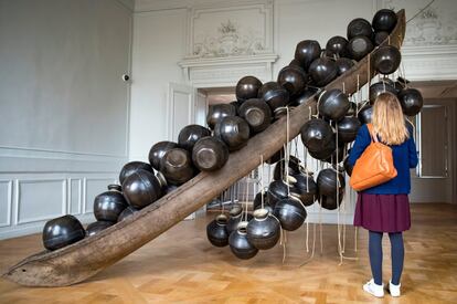 Una visitante observa la obra "Jal Mein Kumbh, Kumbh Mein Jal Hai" del artista indio Subodh Gupta en una retrospectiva de su trabajo en el museo Monnaie de París (Francia), el 10 de abril de 2018. La muestra abre al público desde el 13 de abril hasta el 26 de agosto.