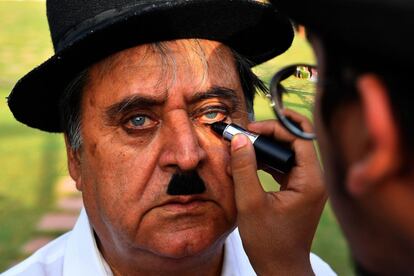 Talin Mavani (d), un imitador de Charlie Chaplin, maquilla a su abuelo, Ashok Aswani (i), fundador del club de fans Charlie Circle durante un evento que conmemora el 129 cumpleaños del legendario actor en Adipur (India).