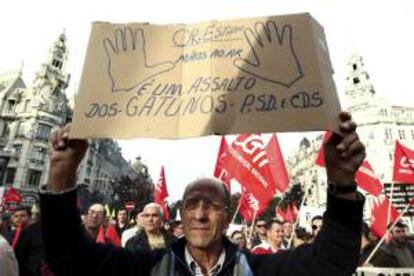 Un hombre sostiene una pancarta en la que se lee "Presupuestos generales del Estado, manos arriba, esto es un atraco de los ladrones del PSD y el CDS" durante una manifestación en contra la Troika. EFE/Archivo