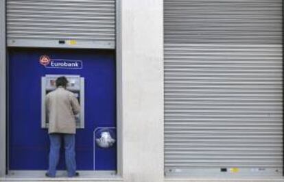 Un cliente utiliza un cajero automático en una sucursal del Banco Nacional de Grecia, en en centro de Atenas, Grecia. EFE/Archivo