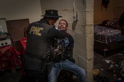 Un agente detiene a un integrante de la sección Crazy Gangsters del Barrio 18 durante un registro en su vivienda en la colonia Santa Faz, en Ciudad de Guatemala.