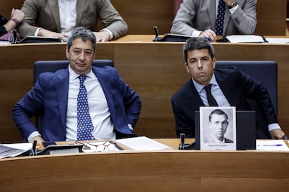 El presidente de la Generalitat, Carlos Mazón (derecha), del PP, junto al vicepresidente primero y consejero de Cultura, Vicente Barrera, del PP, con la fotografía del poeta Miguel Hernández que le ha entregado el portavoz socialista, José Muñoz. 
