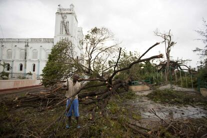 A man cuts a tree felled by Hurricane Matthew, outside the cathedral in Les Cayes, Haiti, Thursday, Oct. 6, 2016. Two days after the storm rampaged across the country's remote southwestern peninsula, authorities and aid workers still lack a clear picture of what they fear is the country's biggest disaster in years. (AP Photo/Dieu Nalio Chery)