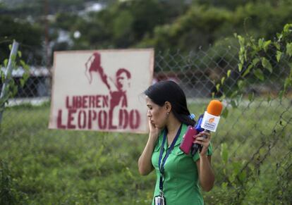 Una periodista habla por teléfono delante de un cartel del líder encarcelado. La defensa de Leopoldo López ya ha anunciado que recurrirá la sentencia, que considera una de las más duras de las que se barajaban antes de la vista final y constata el largo proceso de deterioro de la justicia venezolana.