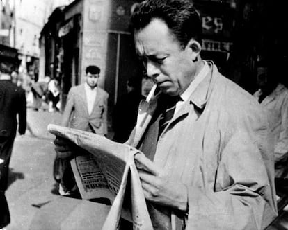 Albert Camus, fotografiado mientras fuma y lee el periódico en París, en 1953.