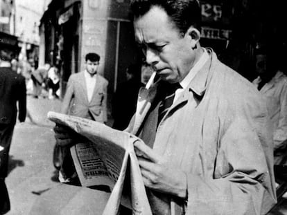 Albert Camus, fotografiado mientras fuma y lee el periódico en París, en 1953.