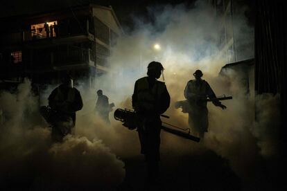 Voluntarios de Sonko Rescue Team, una ONG privada fundada por el gobernador de Nairobi Mike Sonko, fumigan una calle de un barrio residencial de la capital de Kenia.