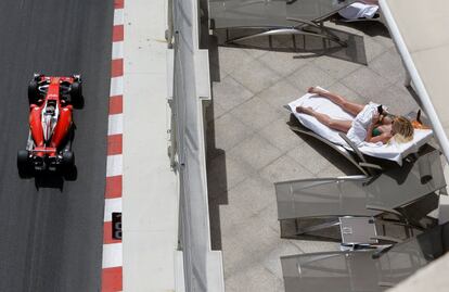 El piloto de Ferrari Sebastian Vette, conduce durante la segunda sesión de entrenamientos libres en el circuito de Mónaco, mientras una mujer toma el sol en un hotel.
