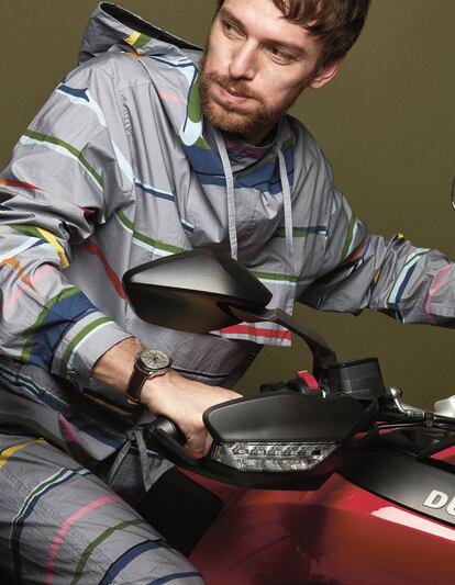 Sobre una Ducati Multistrada 950, cortavientos y pantalón estampado en tejido técnico Lacoste. Reloj Longines Master Collection Moonphase.
