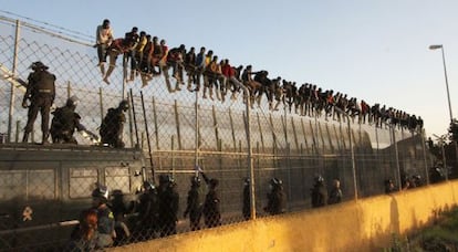 Decenas de inmigrantes encaramados a la valla de Melilla.