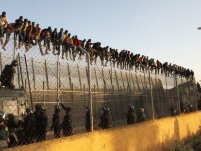 Decenas de inmigrantes encaramados a la valla de Melilla.