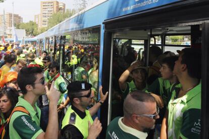 Decenas de jóvenes tratan de subir a un autobús de la EMT en Aluche para llegar al aeródromo de Cuatro Vientos.