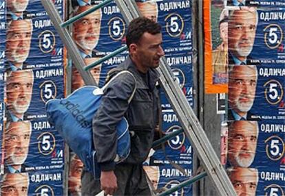 Un hombre pasa por delante de los carteles del candidato Labus a las elecciones serbias, en Belgrado.