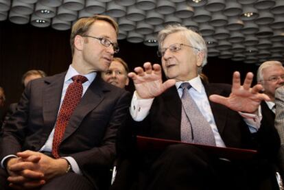 Weidmann (izquierda) conversa con Trichet en la toma de posesión del primero, ayer en Fráncfort.