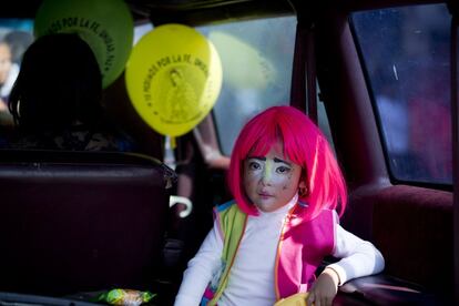 Una niña vestida de payaso en la parte trasera de un coche después de la procesión a la Basílica.