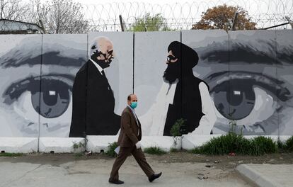 Un hombre con una mascarilla pasa ante un mural que alude al acuerdo entre EE UU y los talibanes en el centro de Kabul.