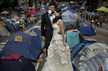 Una pareja se fotografía para sus fotos de boda entre las tiendas de campaña de los manifestantes prodemocracia en una calle de Hong Kong. Representantes de los manifestantes prodemocráticos de Hong Kong tienen previsto viajar a Pekín para reunirse con representantes del Gobierno central y pedirles libertad democrática en las próximas elecciones en 2017.