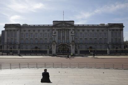 Una persona se sienta en los escalones del monumento a la Reina Victoria mientras contempla el palacio de Buckingham en Londres (Reino Unido), el 23 de marzo de 2020.
