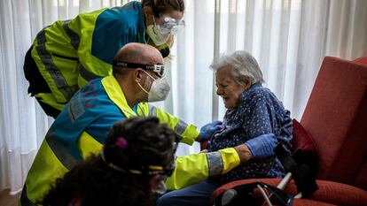 Health workers help an elderly patient in Madrid.