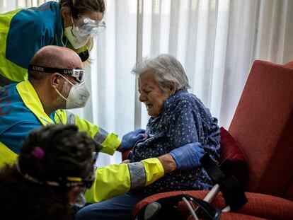 Health workers help an elderly patient in Madrid.