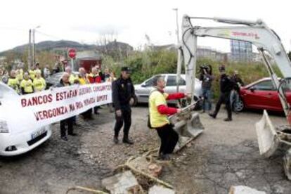 Afectados por las participaciones preferentes permanecen concentrados ante la explanada de la nueva depuradora de Vigo, durante la visita que diversas autoridades han realizado a las obras de esta infraestructura. Los concentrados instalaron en el acceso a las obras una barricada con bloques de cemento y troncos de col, que, no obstante, permitieron que fuera retirada posteriormente por una excavadora.