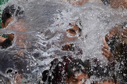 Jóvenes paquistaníes se refrescan con agua de un pozo durante la ola de calor en Lahore (Pakistán). Las condiciones de la ola de calor en Pakistán han alcanzado temperaturas de más de 42 grados centígrados en muchas partes del país.