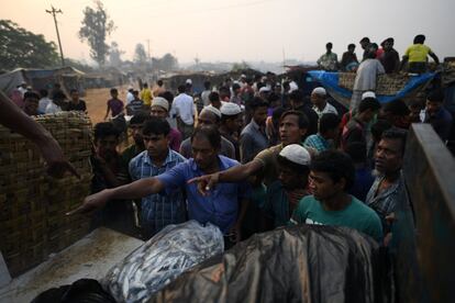 Unos refugiados rohingya hacen gestos a los vendedores de pescado en el mercado del campamento de refugiados de Kutupalong, en Cox's Bazar (Bangladesh)