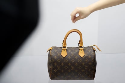 Un vendedor sujeta un bolso de LVMH en una sesión de fotos para una tienda de artículos de lujo de segunda mano, en Pekín, en el mes de octubre.