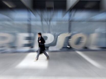 File photo of a woman walking past the logo of Spanish oil major Repsol at its headquarters in Madrid