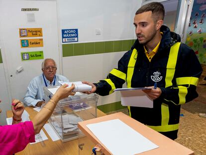 Un cartero entrega el voto por correo en una mesa electoral, el 28-M.