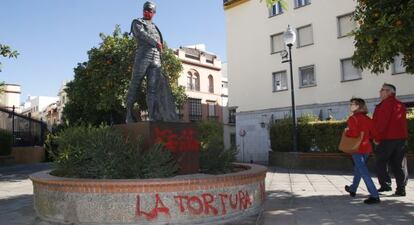 Una pareja mira la escultura de Curro Romero con las pintadas, en Sevilla.