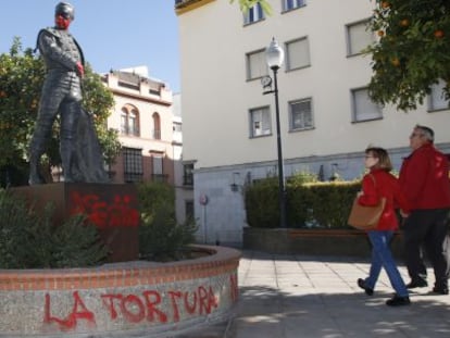Una pareja mira la escultura de Curro Romero con las pintadas, en Sevilla.