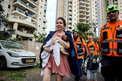Personal de rescate evacúan a una mujer y sus hijos de un complejo residencial afectado por un misil iraní, en el centro de Israel.