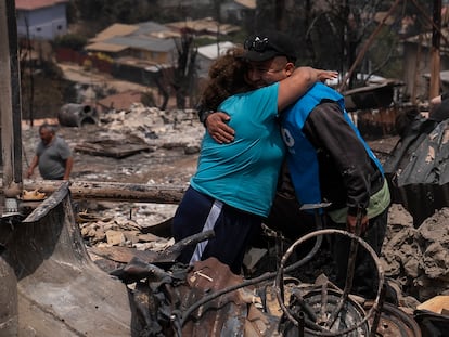 Dos personas se abrazan entre los restos de una vivienda en Achupallas, en la región de Valparaíso (Chile), el pasado domingo.