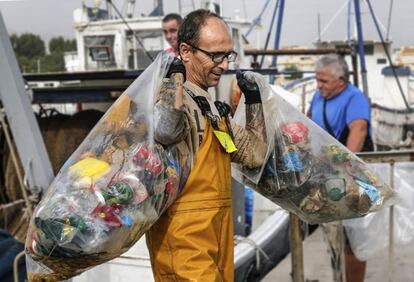 Un pescador lleva la basura sacada del mar a los contenedores habilitados en el puerto de Vila Joiosa (Alicante) para su depósito.