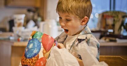 Un niño abre un regalo en Navidad.