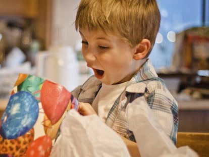 Un niño abre un regalo en Navidad.