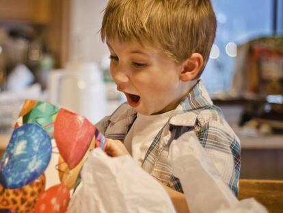 Un niño abre un regalo en navidad.