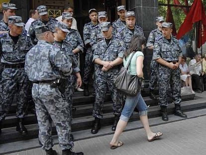 Una mujer pasa delante de miembros de las fuerzas especiales que vigilan la sede de la Fiscalía General de Ucrania ayer en Kiev.