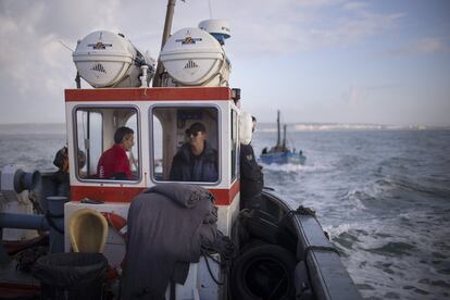 El capitán de uno de los barcos que participa en la pesca de atún de almadraba maneja el timón. Al fondo la localidad de Barbate.