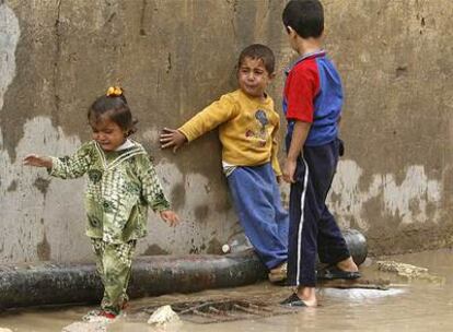 Unos niños lloran porque no pueden cruzar la calle en un día de lluvia en el barrio de Sadr City de Bagdad.