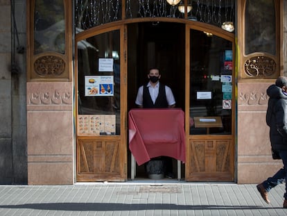 En la imagen, un camarero en la Rambla de Barcelona espera desde la puerta del establecimiento la llegada de algún cliente.