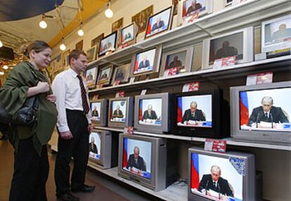 Una cliente y un vendedor siguen por televisión la intervención del presidente Putin en Moscú.