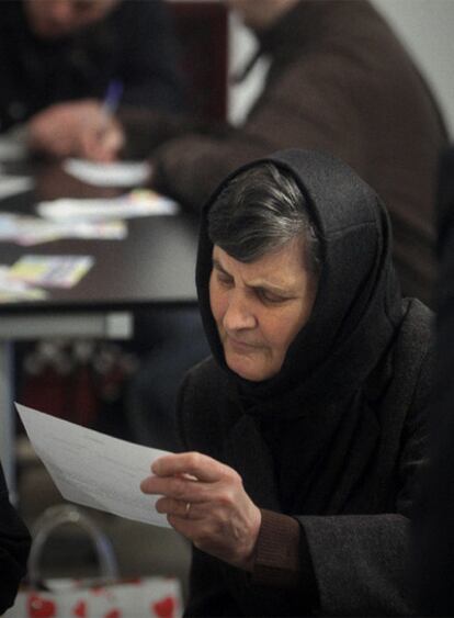 Una mujer rumana examina una papeleta para elegir al presidente de su país.