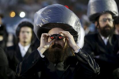 An ultra-Orthodox Jewish man uses binoculars during the wedding ceremony the grandson of Rabbi Yosef Dov Moshe Halberstam, religious leader of the Sanz Hasidic dynasty and the granddaughter of the religious leader of Toldos Avraham Yitzchak Hasidic dynasty, in Netanya, Israel March 15, 2016. Picture taken March 15, 2016. REUTERS/Baz Ratner      TPX IMAGES OF THE DAY     