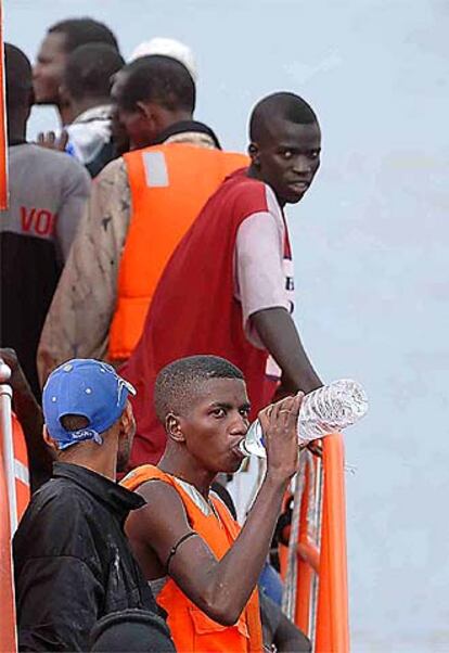 Un grupo de inmigrantes interceptados en una embarcación se refresca en el puerto de los Cristianos.