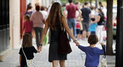 Una madre lleva a sus hijos al colegio.